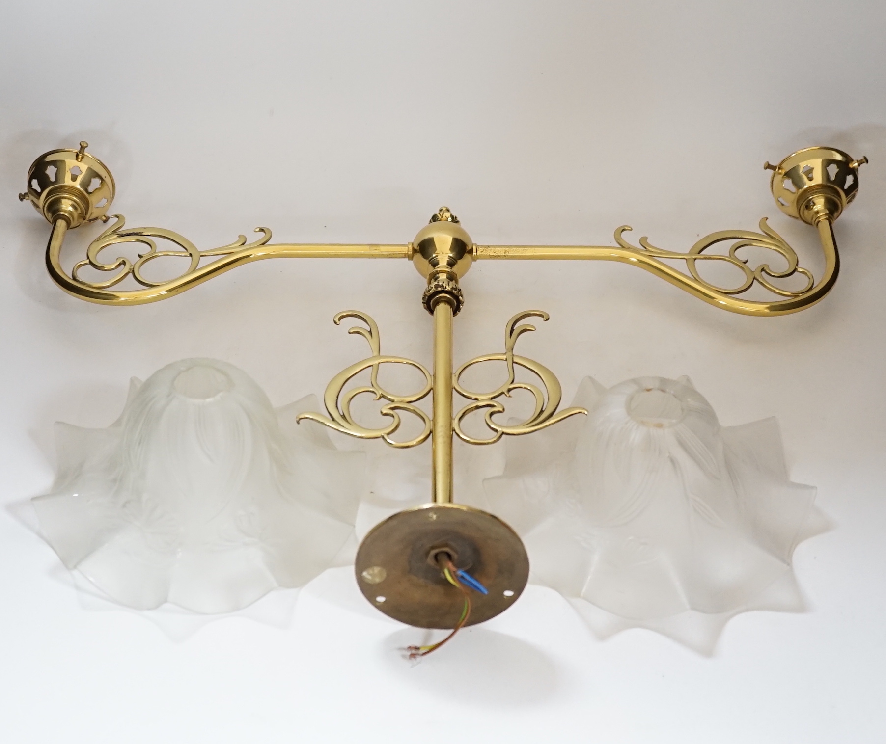 A brass pendant light and two opaque glass frilled shades, 60cm wide
